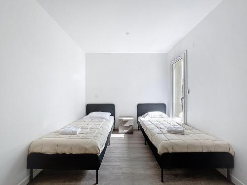 two beds in a room with white walls at Belle maison sur Cournon 10 pers Chataigniers in Cournon-dʼAuvergne