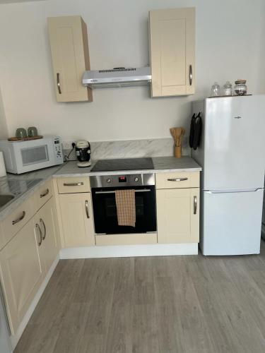 Il comprend une cuisine équipée d'une cuisinière et d'un réfrigérateur blanc. dans l'établissement Appartement cosy T2 avec balcon proche de CDG et de Paris, au Blanc-Mesnil