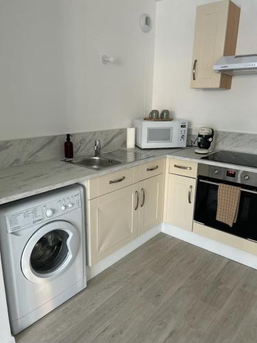 une cuisine avec une machine à laver et un évier dans l'établissement Appartement cosy T2 avec balcon proche de CDG et de Paris, au Blanc-Mesnil