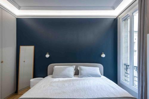 une chambre bleue avec un lit et une fenêtre dans l'établissement Cozy Paris apartment, à Paris