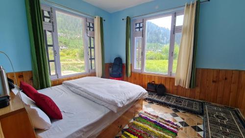 a bedroom with a bed and two windows at Himalayan Horizon Deohari in Sainj