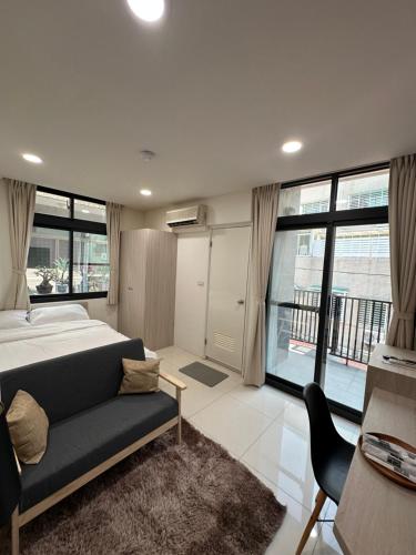 a bedroom with a bed and a couch and windows at 隱居末巷 in San-fen-tzu
