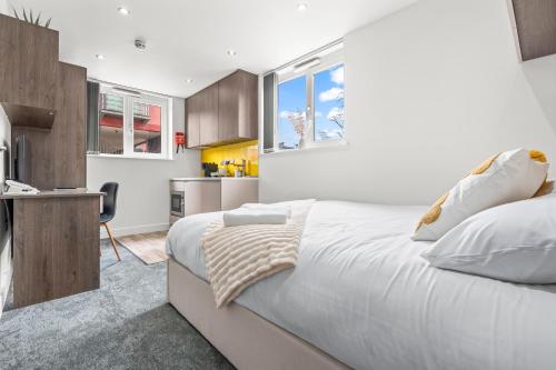 a bedroom with a large white bed and a kitchen at Contemporary Comfort Steps from Ricoh Arena in Coventry