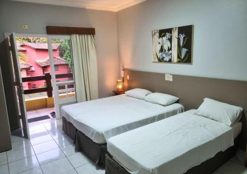 two beds in a hotel room with a window at Flat Incrível Amarilis dentro da Riviera São Lourenço - 2 Unidades disponíveis, Duplex 2 Quartos, Cozinha e Varanda ou Unidade tipo Estúdio sem Cozinha in Riviera de São Lourenço