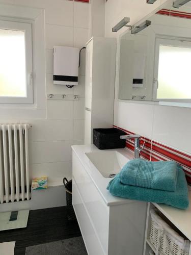 une salle de bain blanche avec un lavabo et un miroir dans l'établissement La Villa Brise Marine, à Leffrinckoucke