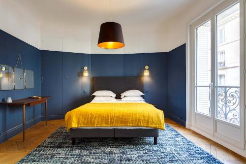 - une chambre avec des murs bleus et un lit avec une couverture jaune dans l'établissement Habitat Parisien - Courcelles Parc Monceau, à Paris