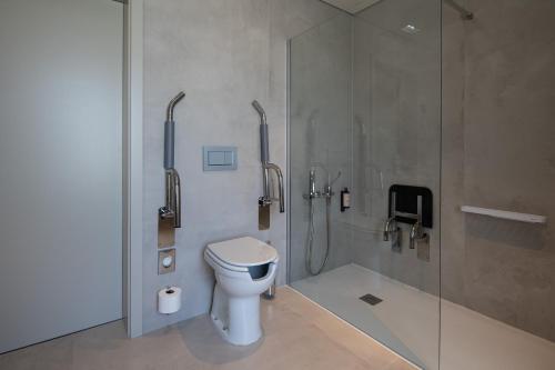 a bathroom with a toilet and a glass shower at Mercure Ponta Delgada Azores in Ponta Delgada
