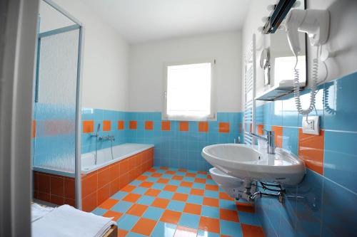 un bagno blu e arancione con lavandino e vasca di amaranto bnb a Matera