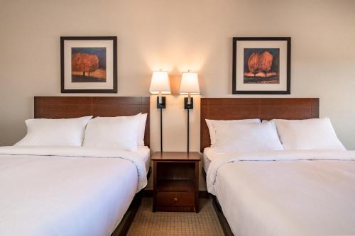 two beds in a hotel room with two lamps at Canalta High River in High River