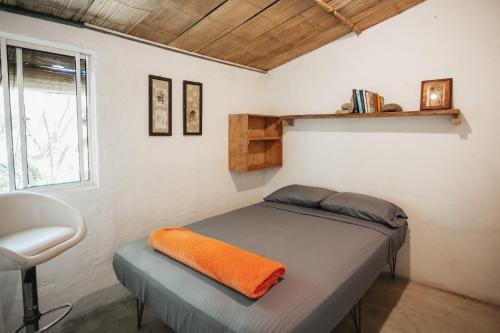 Un dormitorio con una cama con una manta naranja. en Casa blanca, Refugio Natural Jacaranda, en Cocorná