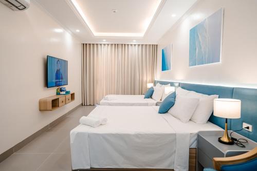 two beds in a hotel room with blue and white at Lotus Sầm Sơn Hotel in Sầm Sơn