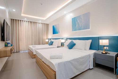 a hotel room with two beds and a television at Lotus Sầm Sơn Hotel in Sầm Sơn