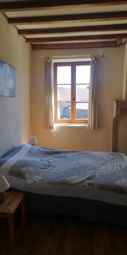une chambre avec un lit bleu et une fenêtre dans l'établissement Le gîte le bastillaume, à La Celle-sous-Gouzon