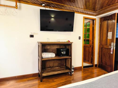 a room with a tv on a wall with a wooden shelf at Casa Candilejas in Bogotá