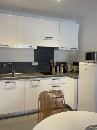 une cuisine avec des armoires blanches et une table et une chaise dans l'établissement Appartement vue Mer en plein centre, à Calvi