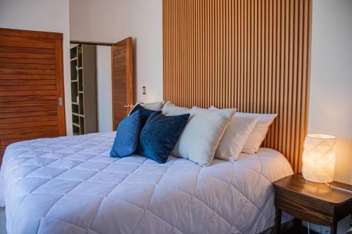 une chambre avec un grand lit blanc avec des oreillers bleus dans l'établissement Condo Cortes Y Club De Playa La Paz, à La Paz