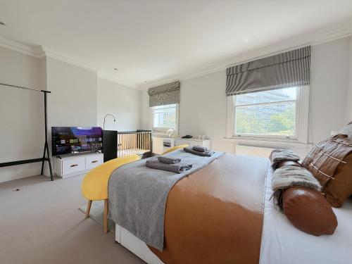 a bedroom with a bed and a flat screen tv at Spacious and cosy 3BRs 5F House in Heart of London in London
