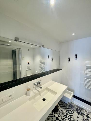 une salle de bain blanche avec un lavabo et un miroir dans l'établissement Douce brise proche océan, à Seignosse