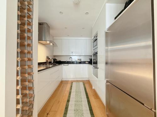 a kitchen with white cabinets and a stainless steel refrigerator at Spacious and cosy 3BRs 5F House in Heart of London in London