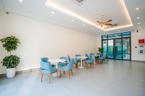 a waiting room with tables and blue chairs at Lotus Sầm Sơn Hotel in Sầm Sơn