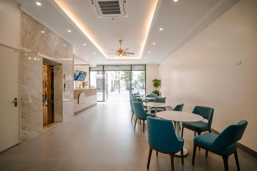 a dining room with tables and blue chairs at Lotus Sầm Sơn Hotel in Sầm Sơn