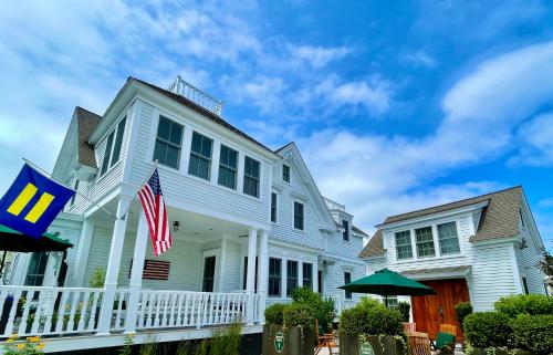 a white house with an american flag on the porch at White Porch Inn in Provincetown