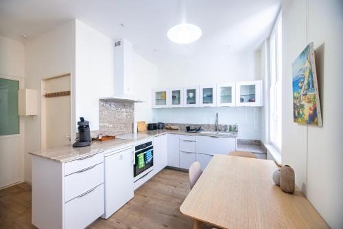 une cuisine avec des armoires blanches et une table en bois dans l'établissement Centre-ville, proche port, à La Ciotat