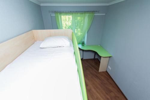 a small bedroom with a bed and a green chair at Seven Apart Hotel in Vyshneve