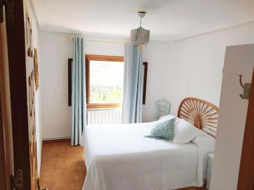 a bedroom with a white bed and a window at Mirador de Palacios- céntrico con vistas y parking cerca in Albarracín