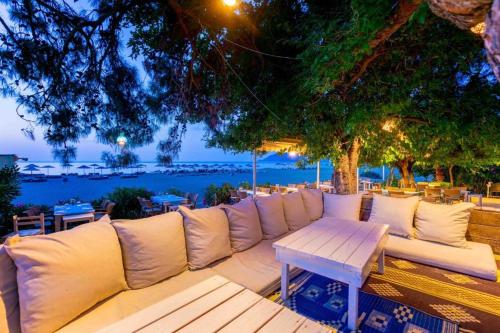 a white couch sitting under a tree with a table at Etenna Beach Bungalows in Cıralı