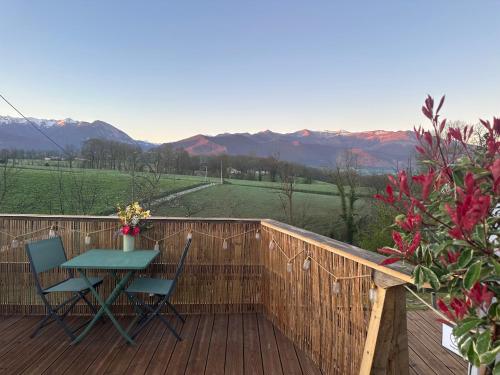 a table and chairs on a deck with mountains in the background at L'étoile du Béarn in Asson