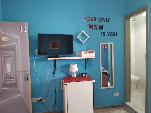 a bathroom with a blue wall with a tv on a counter at La capannina cilento num 11 in San Marco di Castellabate