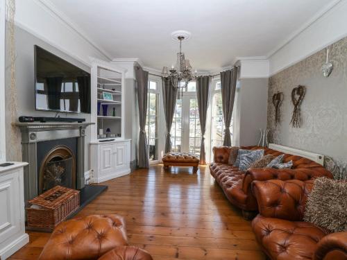 a living room with a leather couch and a fireplace at Albany in Looe