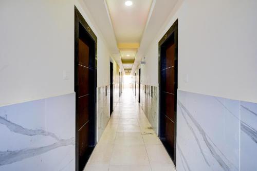a corridor in a building with white walls and marble floors at Hotel O Sri Vishnu Prime Opposite The Studio Salon, Kundalhalli Gate in Bengaluru