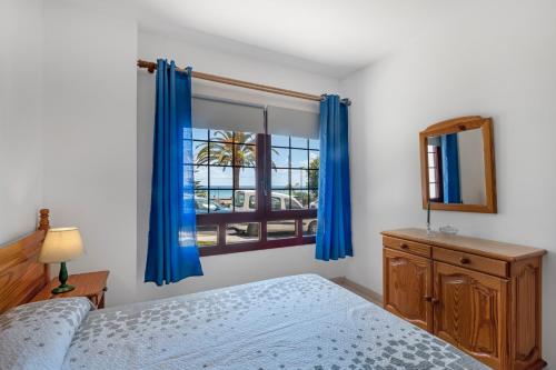 a bedroom with a bed and a window with blue curtains at Piso Tazacorte in Puerto