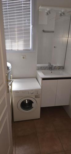 - une cuisine blanche avec un lave-linge et un évier dans l'établissement jolie appartement pour 4 personnes à propriano, à Propriano