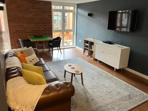 a living room with a leather couch and a table at For Students Only Corner House in Sheffield in Sheffield