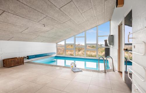 a swimming pool in a room with a large window at Cozy Home In Hjørring With Sauna in Lønstrup