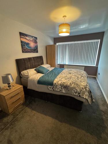 a bedroom with a bed and a lamp and a window at Modern 3-Bed Family Home in Quiet Sheffield Area in Wincobank