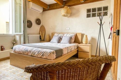 - une chambre avec un lit et un fauteuil en rotin dans l'établissement La l'Isloise douceur de vivre à la Provençale, à LʼIsle-sur-la-Sorgue