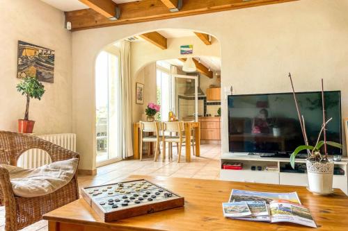 a living room with a large television and a table at La l'Isloise douceur de vivre à la Provençale in LʼIsle-sur-la-Sorgue