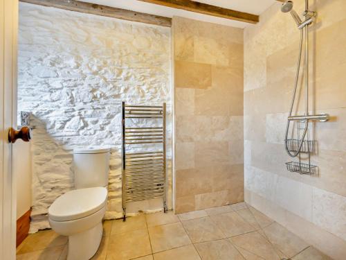 a bathroom with a toilet and a stone wall at 3 Bed in Threkeld 93590 in Threlkeld