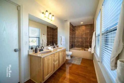 a bathroom with a sink and a toilet and a mirror at Hill Country Beauty in Red in Cedar Park