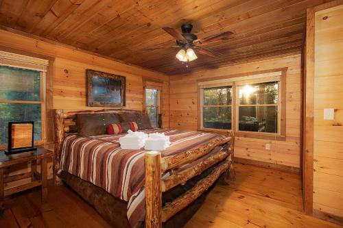 a log cabin bedroom with a bed and a ceiling fan at Majestic View in Mashburn Mill