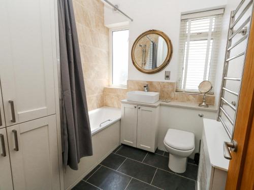 a bathroom with a toilet and a sink and a mirror at Flat 7 Sand Acres in Poole