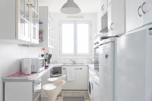 La cuisine blanche est équipée d'un réfrigérateur et d'un évier. dans l'établissement Apartment for 3 overlooking the Eiffel Tower, à Boulogne-Billancourt