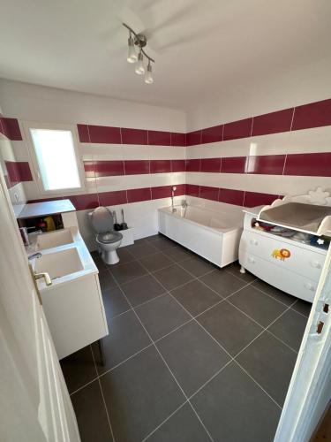 La salle de bains est pourvue d'une baignoire blanche et de rayures rouges et blanches. dans l'établissement Villa familiale avec piscine chauffée, à La Lande-de-Fronsac