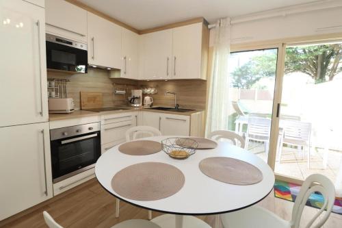 une cuisine avec une table blanche et une table et des chaises dans l'établissement Le Belouga By Tranquil at Home, à Pornichet
