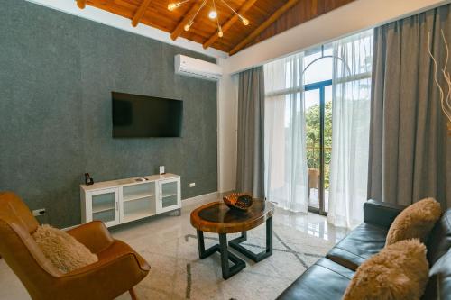 a living room with a couch and a tv at Hotel San Bada Resort & Spa in Manuel Antonio