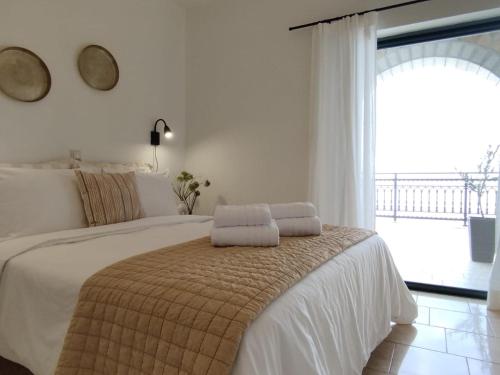 a white bedroom with a bed with two pillows on it at Selini Apartments Mani in Agios Nikolaos